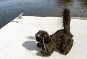 scaring birds away from boat - decoy crouching cat on dock